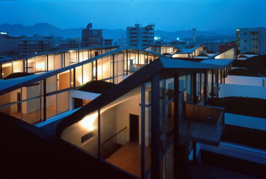 Nexus Housing • Location: Fukuoka, Japan • Architect: Rem Koolhaas of OMA • Built: 1991 • Units: 24 Notable: To emphasize the inversion of the typology, Koolhaas designed the perimeter wall of the housing out of large, dark basalt stones, echoing the Japanese castle wall while making the roofscape white and as visually fluid as possible.