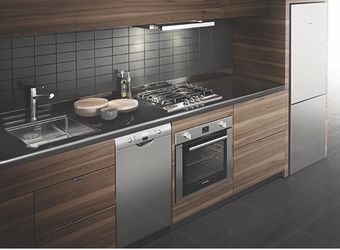 Breaking up the stove and dishwasher with an undercounter oven and separate cooktop allows the front edge of the counter to run continuously across the length of a small kitchen, reducing visual chaos.