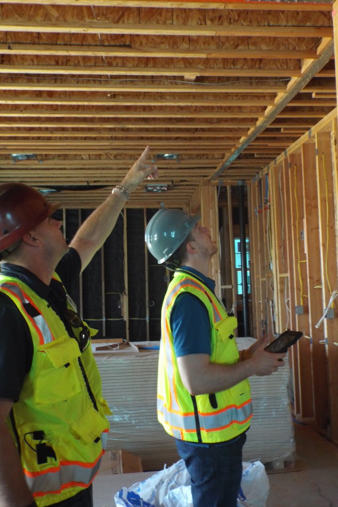 Inspectors examine a ceiling assembly.