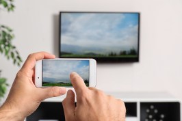 Woman with smartphone connected to TV set in living room