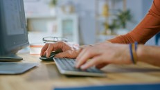 Handsome Software Engineer Works on a UX / UI Mobile App Template, Uses Personal Computer. Freelance Programmer Working from Cozy Living Room.