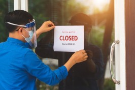 The store manager wore a blue shirt, closing the signboard saying "Closed due to Covid-19" at the front door glass.