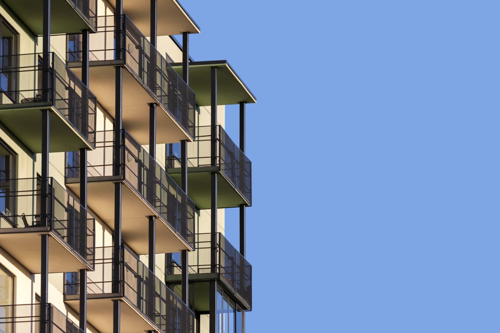 Modern apartment building with balconies against blue sky to ad text