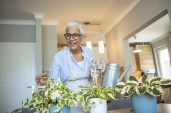 Senior Woman With Green Plants and Flowers at home. Senior Woman Caring for House Plant. Woman Taking Care of Plants at Her Home Portrait of Elderly Woman Gardening at Home. Retired Female Care for Her Plants