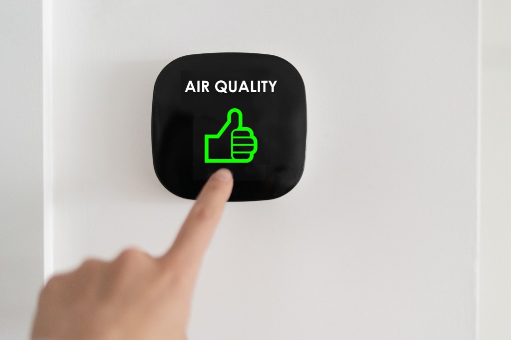 Good air quality indoor smart home domotic touchscreen system. air. Woman touching touchscreen checking air purifier filter at green level with thumbs up graphics.