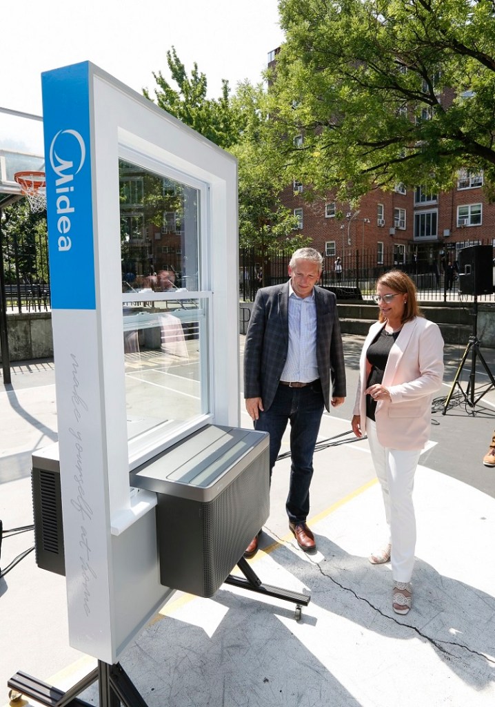 Kurt Jovais, president of Midea America Corp., and Doreen Harris, president and CEO of the New York State Energy Research and Development Authority, inspect a Midea product display at Woodside Houses, a public housing community in New York City. Midea America Corp. is developing new new heat pump technology to decarbonize New York City Housing Authority buildings.