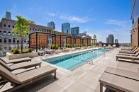 The rooftop of Hubbard221 in Chicago features a pool, a hot tub, cabanas, and a lounge area complete with dining tables, a fire pit, several grill setups, and an outdoor TV.