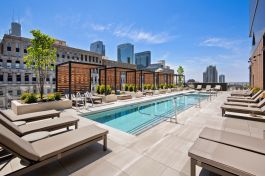 The rooftop of Hubbard221 in Chicago features a pool, a hot tub, cabanas, and a lounge area complete with dining tables, a fire pit, several grill setups, and an outdoor TV.