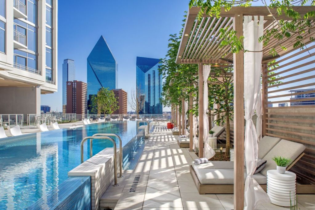 The resort-style infinity-edge pool at Atelier in Dallas is flanked with cabanas along one side and inlay loungers along the other.