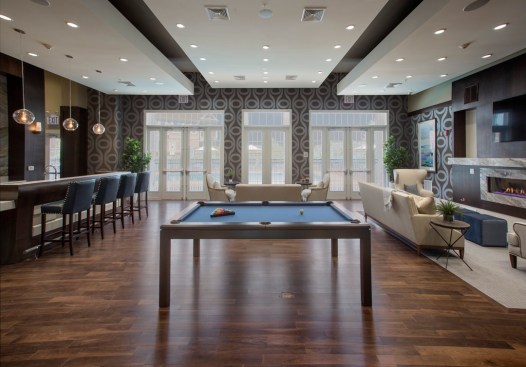 The large, social clubhouse with billiards table, bar, fireplace, and sleek decor reflects the idea of having one large space with areas carved out for more-private gatherings. Its design lends the feeling of a resort or club; hence the project's name, The Club at Pearl River.