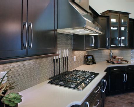 For a sophisticated look, you can’t go wrong with a neutral palette that puts the emphasis on texture. Bielinski Homes did just that in this model home, “The Preston” in Pewaukee, Wisc. Glass tiles in varying lengths and widths provide a stylish middle ground between the dark espresso cabinets and creamy Zodiaq quartz countertop. “Traditionally kitchens in suburban Milwaukee offer oak or light maple cabinetry…and warm color finishes,” says the builder. “We made the decision to go against the grain and create a more urban, streamlined look. The base of this palette is “greige” – gray that incorporates the warmer elements of beige.” 
www.bielinski.com