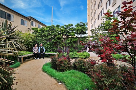 A couple enjoys the garden park at Golden West Tower, a Vitus affordable housing development for seniors in Torrance, Calif. The property also offers residents a library, a computer lab, fitness classes, and many social activities.
