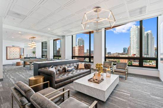 The renovated entertainment and game lounge at Hubbard Place features individual seating areas, a pool table, and a wall-mounted Scrabble board.