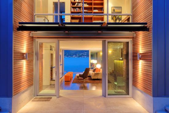 Standing up to all kinds of weather, this lakefront home is skinned on two sides with durable standing seam metal. Then it softens in the middle with an inset front entry that’s clad in warm red cedar. Two sets of glass doors provide a telescopic view through the house to the water beyond. 
Architect: Ray Johnston Architects 
Builder: Schuchart Dow, Seattle