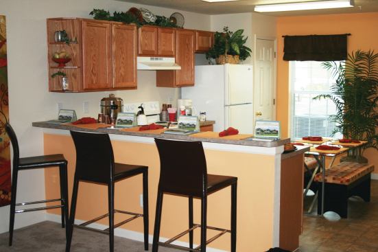 The compact kitchens reflect an attractive mix of form and function, with wood cabinets, colorful laminate countertops, pull-out drawers in base cabinets, and heavy, wear-resistant vinyl floors that were installed using low-VOC glue.