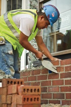 Workers lay brick along the first-floor perimeter starting at one end of the development and working down to the other. 