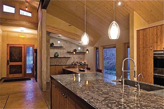 The kitchen center island concrete countertop is shown in the foreground with one of the concrete shear walls in the background.

